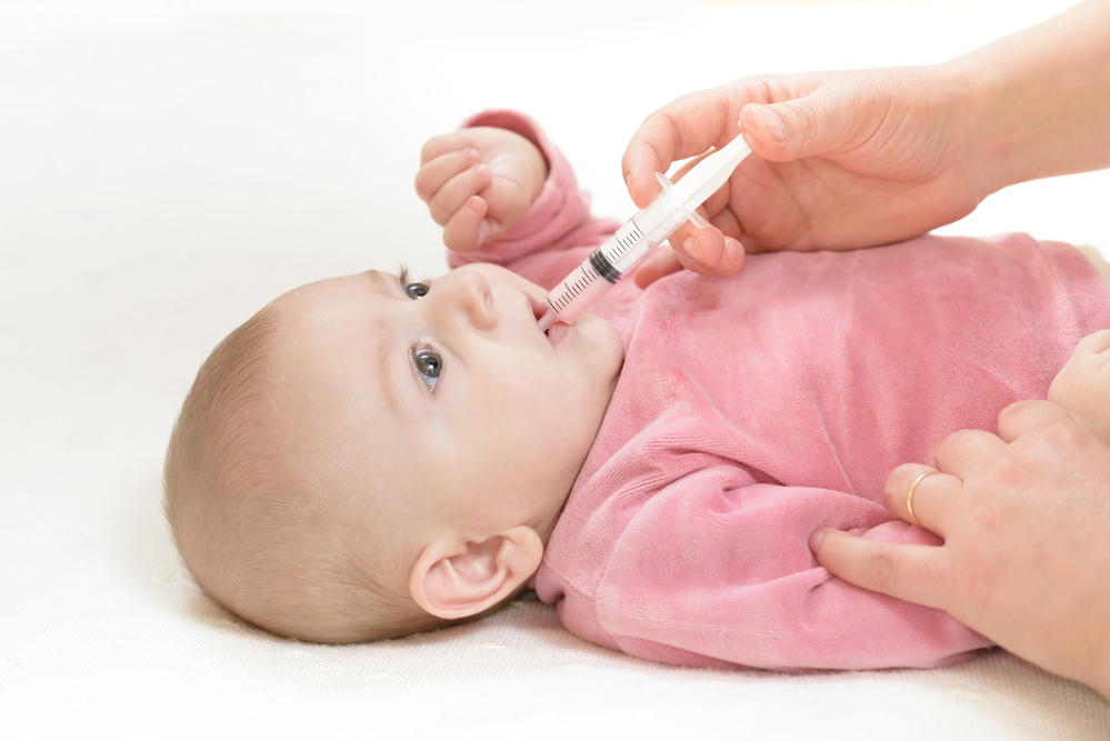 Baby taking medicine from syringe