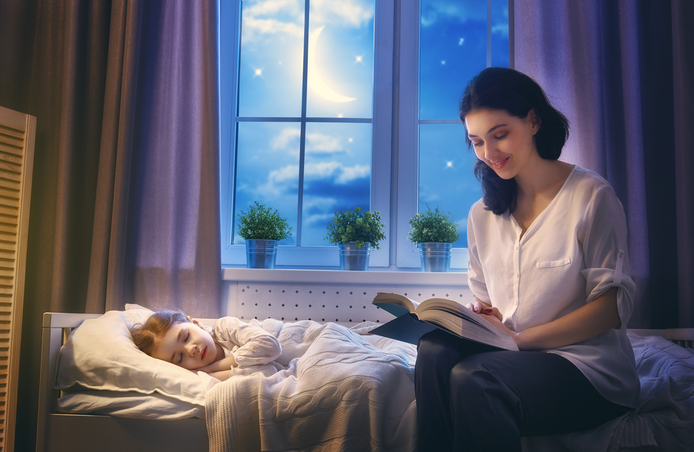 Mum reading to toddler in bed